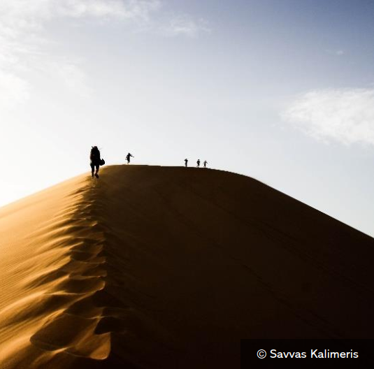 people walking across the desert