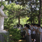 Estudiantes rezando frente a la estatua del Sagrado Corazón en el jardín